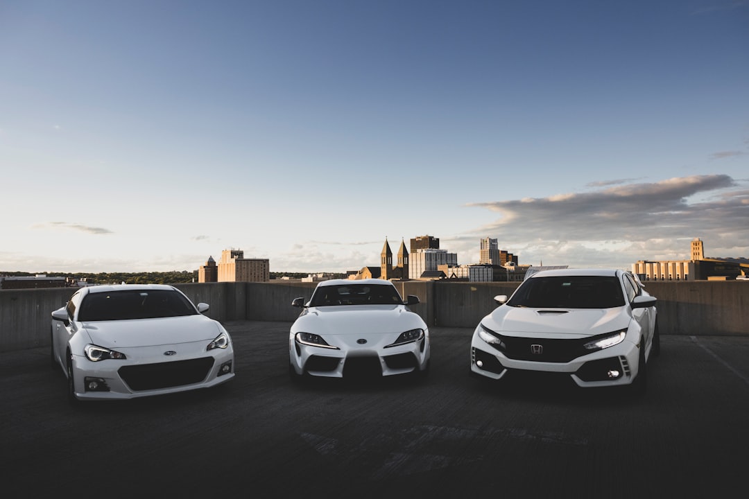 three white cars are parked in a parking lot