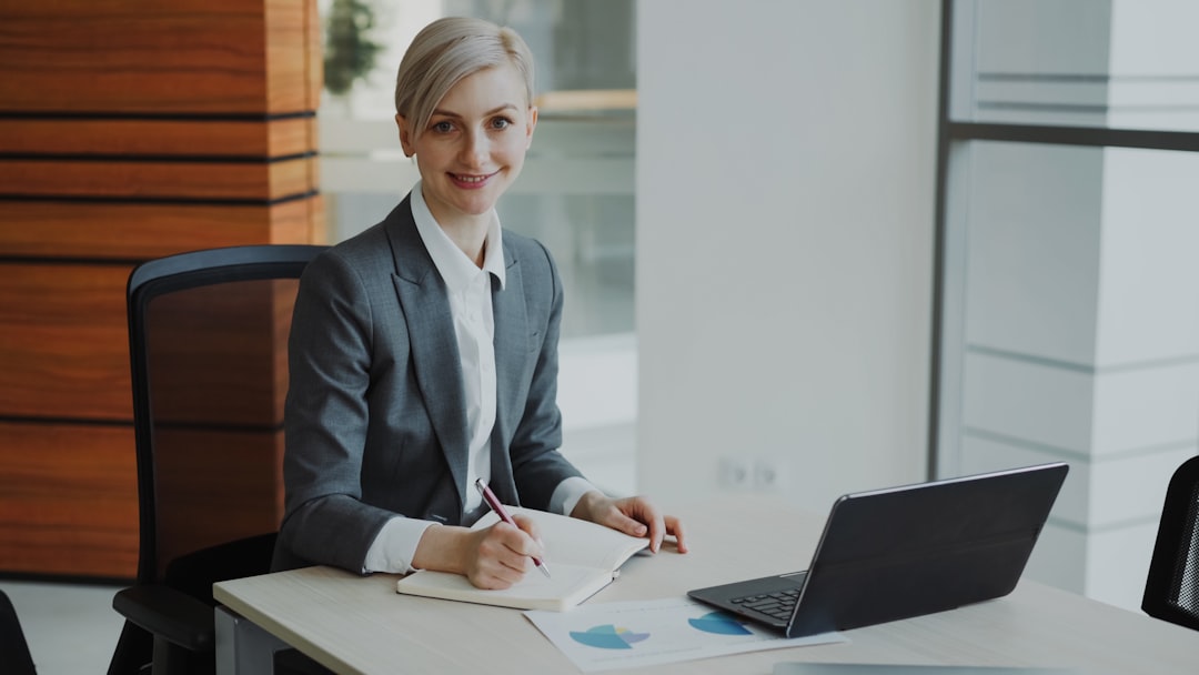 A professional woman in a suit works at a desk.