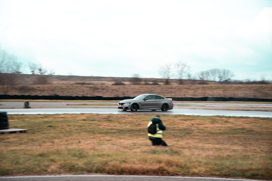 a car driving down a road next to a field
