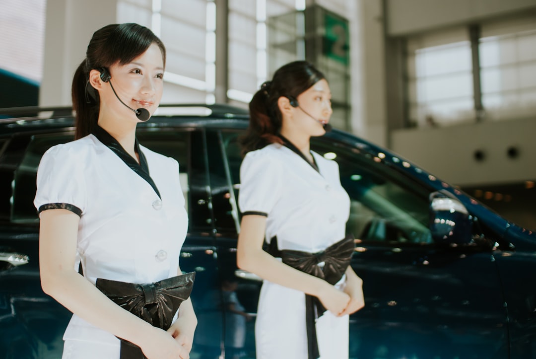 Two women in uniform standing near a car