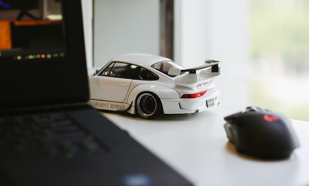 a toy car sitting on top of a desk next to a laptop