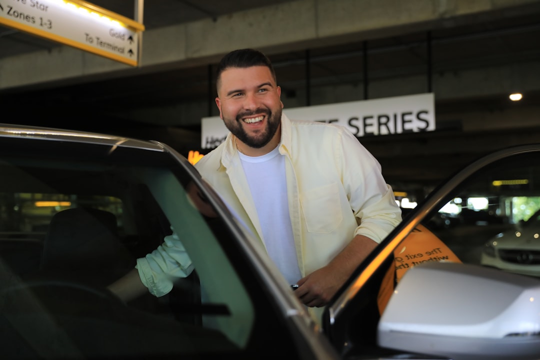 man in white dress shirt standing beside black car