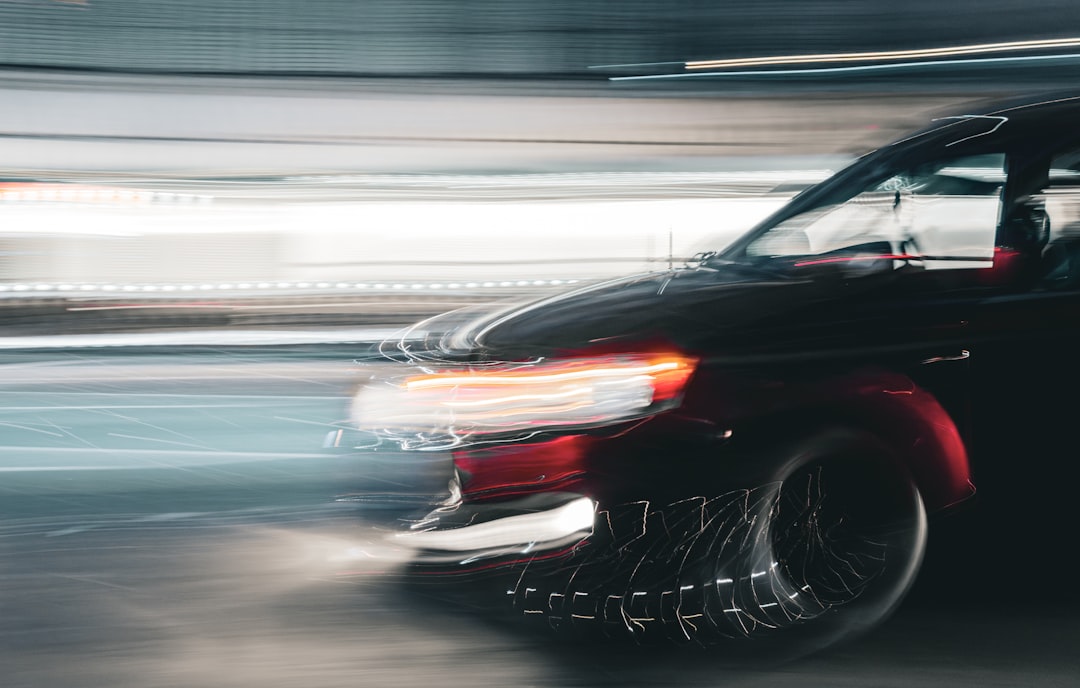 A black car speeds, creating motion blur.